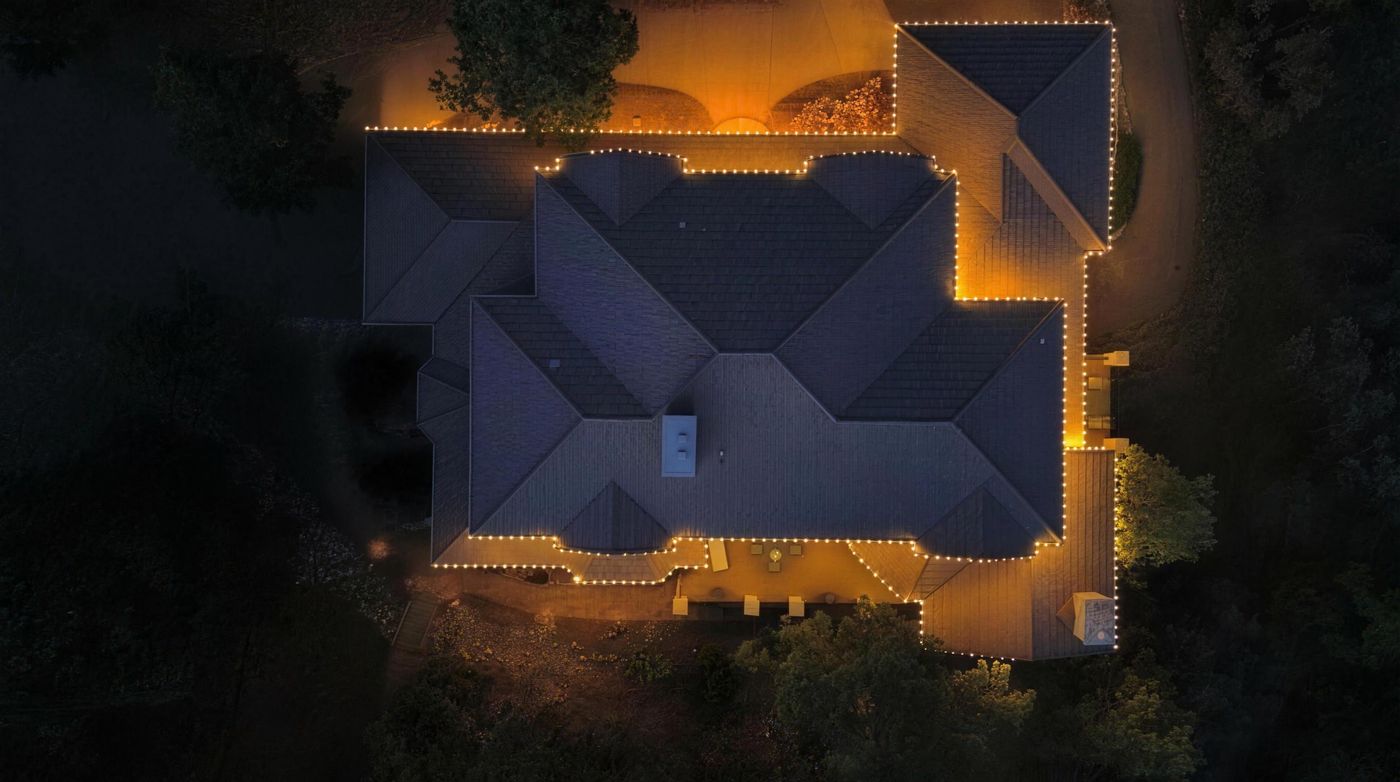 Aerial view of a home with lights tracing every roof edge